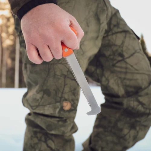 A Casström No.11 Field Saw v.2 in the hand of a person carrying it outside.